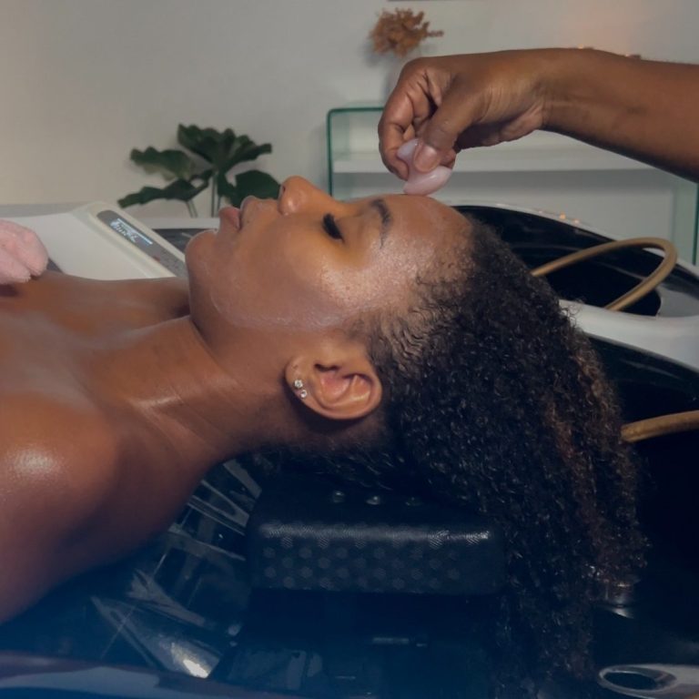 Femme recevant un soin capillaire, allongée, avec une main appliquant un produit.