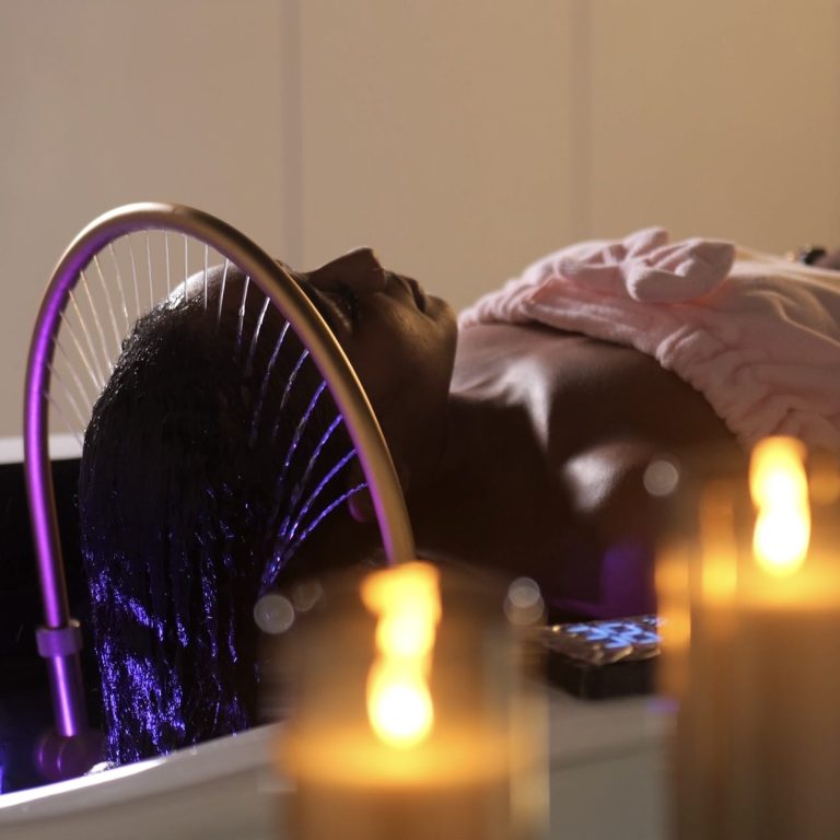 YNAO HEAD SPA GUADELOUPE-TOUS DROITS RESERVES Femme allongée avec un bandeau sur les yeux, recevant un soin au spa.