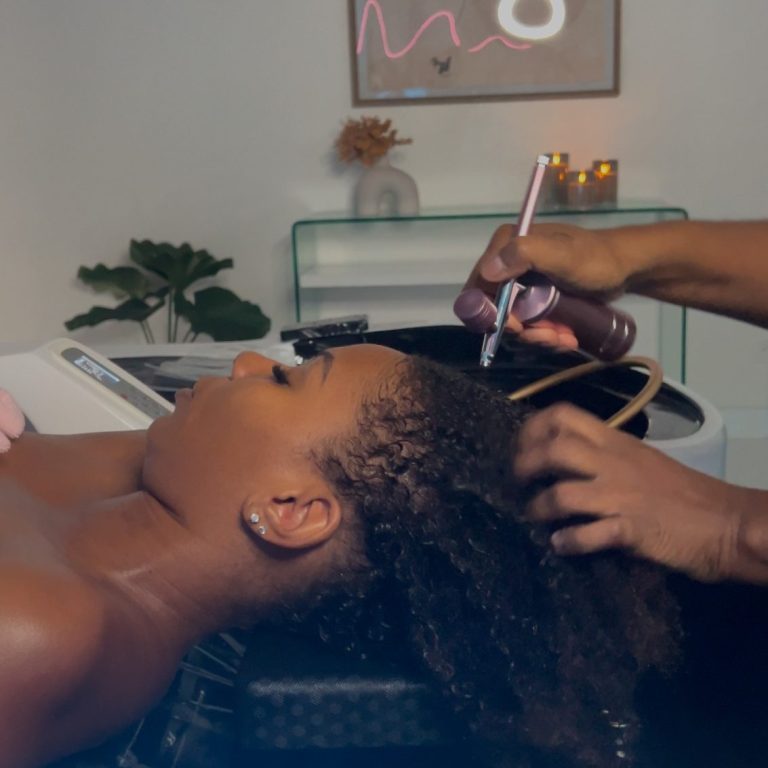 Femme allongée recevant un soin capillaire dans un salon.